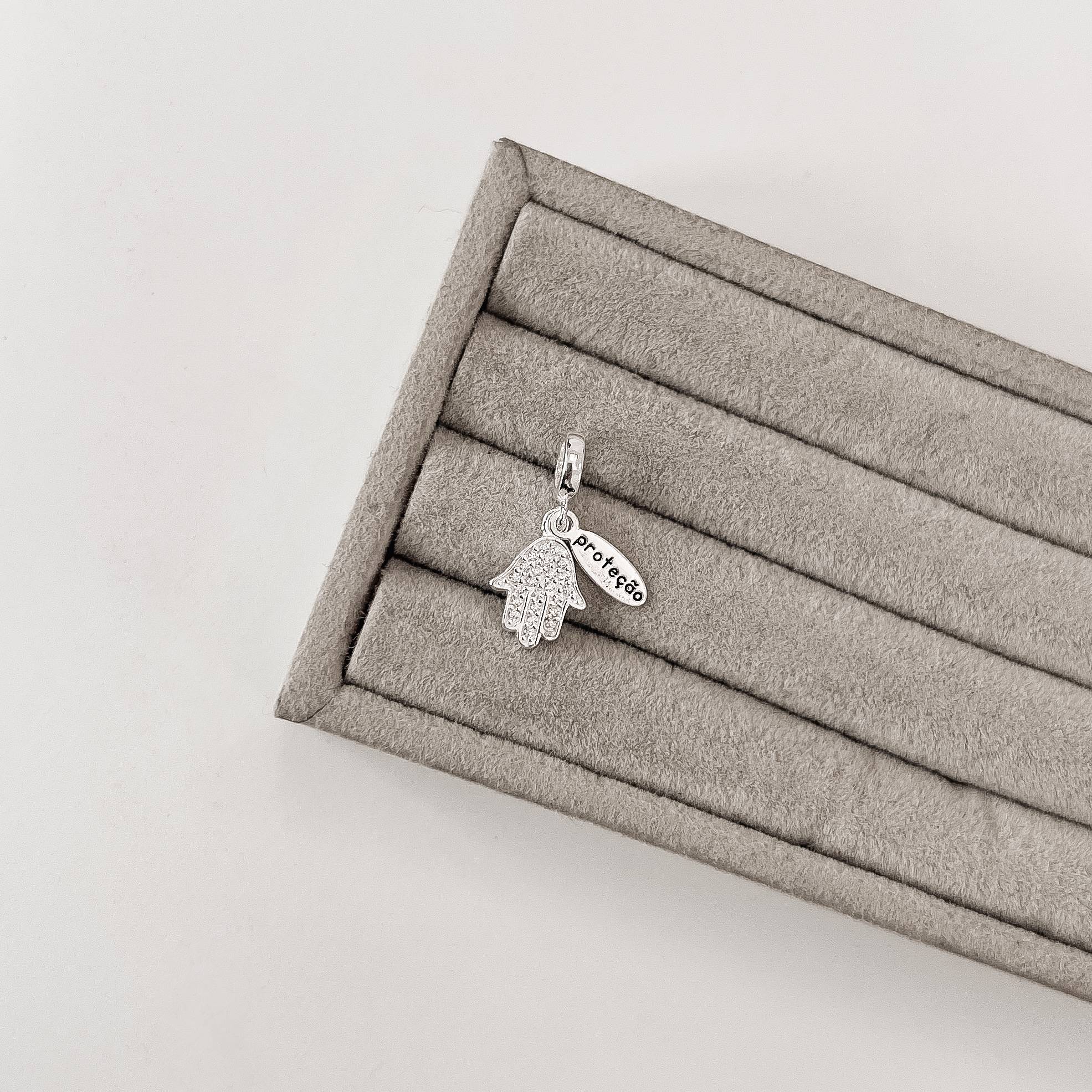 Berloque pingente mão cravejada com placa escrito proteção